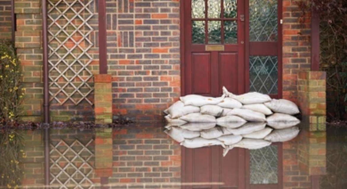 Flooded brick house with sandbags stacked in front of the door.